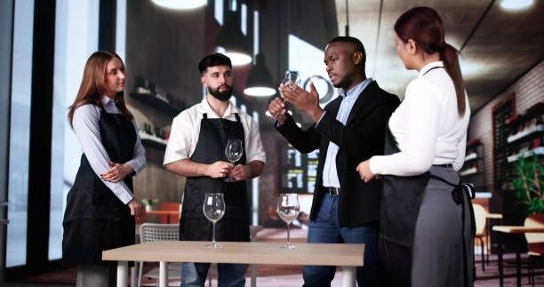 Vier Gastronomiemitarbeitende besprechen gemeinsam den Umgang mit Weingläsern